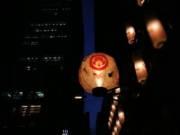 Low angle view of illuminated lanterns hanging in the dark