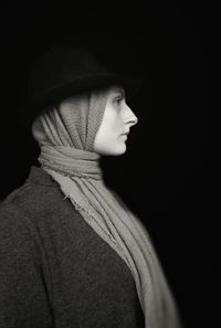 Close-up portrait of a young woman over black background