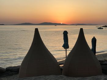 Silhouette people relaxing on beach against sky during sunset on mykonos island 