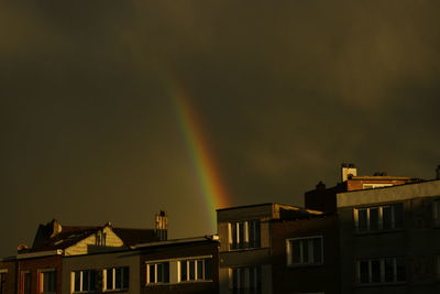 Low angle view of rainbow over buildings against sky