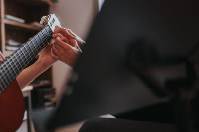Cropped image of teacher teaching student to play guitar in classroom