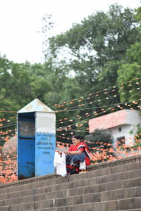 Man sitting on wall against building