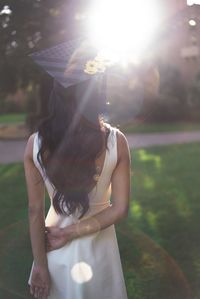 Rear view of young woman wearing graduation hat standing on land