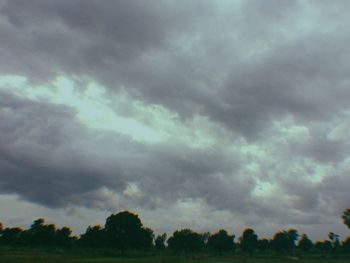 Low angle view of storm clouds over field