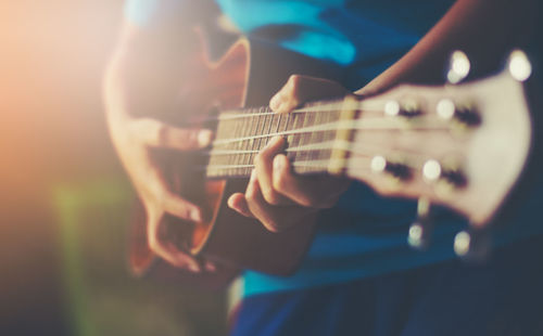 Midsection of man playing guitar