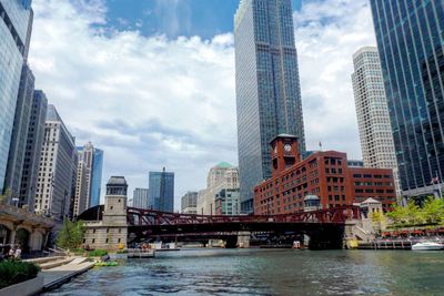 Bridge over river by buildings against sky in city