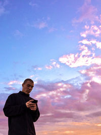 Low angle view of man standing against sky during sunset