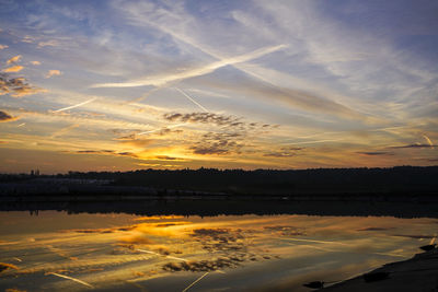 Scenic view of lake against dramatic sky during sunset