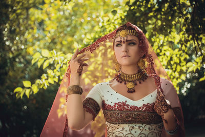 Portrait of young woman standing against plants