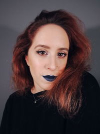 Portrait of beautiful young woman against gray background