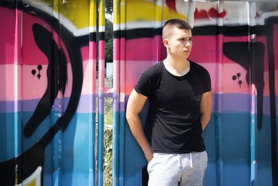 Young man standing against metal