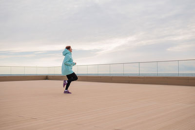 Full length of woman exercising against sky