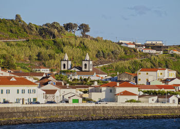 Houses in town by sea against sky