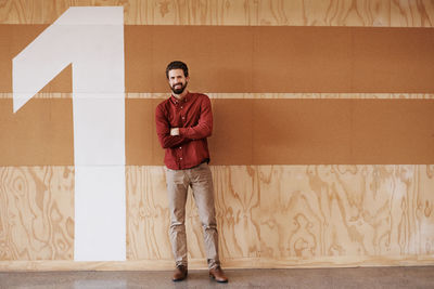 Portrait of young man standing against wall