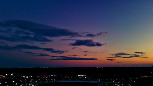 Illuminated city against sky at sunset