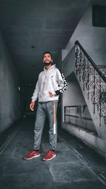 Full length portrait of young man standing against wall