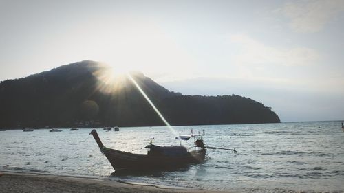 Boat moored on sea against sky during sunset