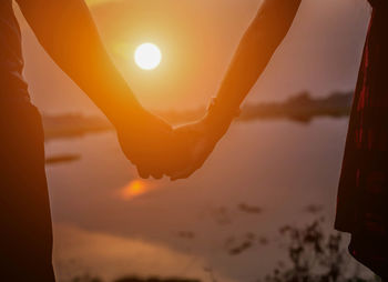 Silhouette hand against sky during sunset