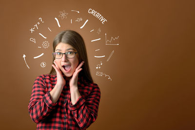 Digitally generated image of surprised young woman against brown background