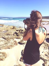 Midsection of woman at beach against clear sky