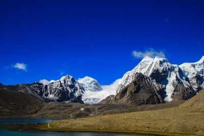 Scenic view of snowcapped mountains against blue sky