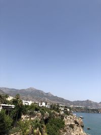 Scenic view of sea and mountains against clear blue sky