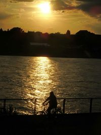 Silhouette people standing by sea against sky during sunset