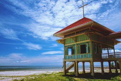 Built structure on beach by sea against sky