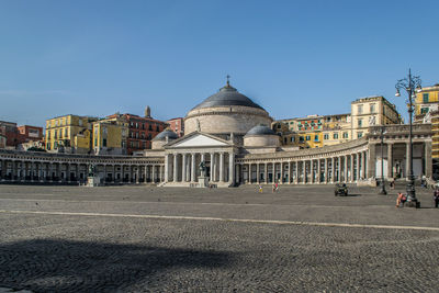 Piazza del plebiscito. a large public square in central naples, italy. buildings against a blue sky.