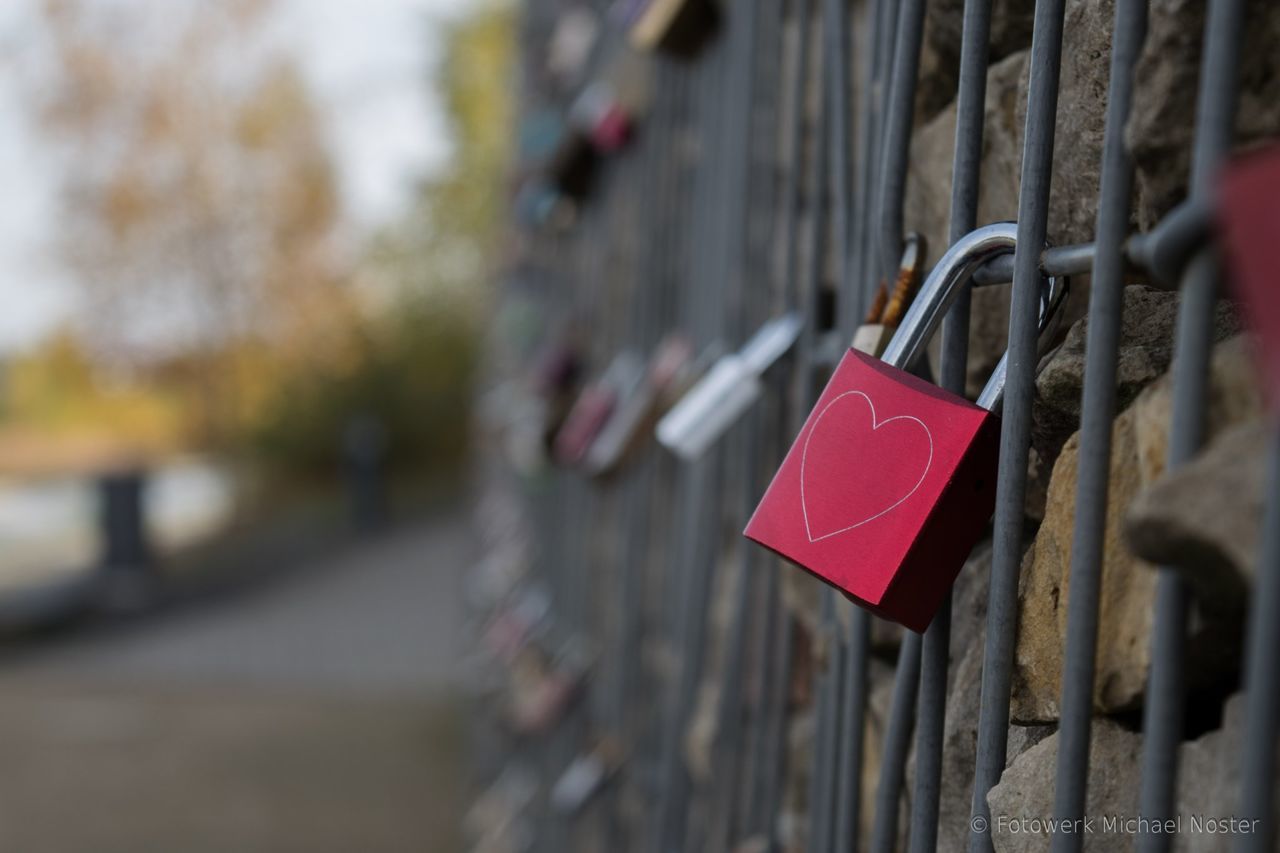 CLOSE-UP OF PADLOCKS HANGING ON RAILING AGAINST BLURRED BACKGROUND