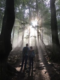 Rear view of man and woman walking in forest