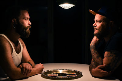 Young man sitting in illuminated room