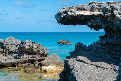 Scenic view of rocks in sea against blue sky