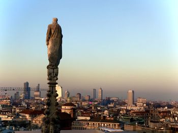 Sculpture and buildings against sky during sunset