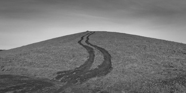 Tire tracks on mountain against sky