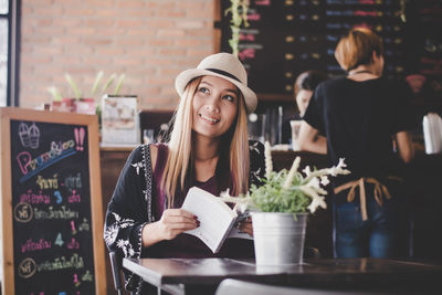 Portrait of smiling young woman standing in restaurant