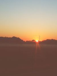 Scenic view of silhouette field against clear sky during sunset