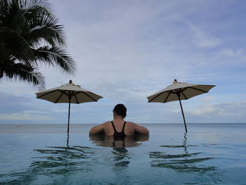 Rear view of shirtless man in sea against sky