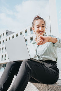 Young woman using laptop while sitting on sofa at home