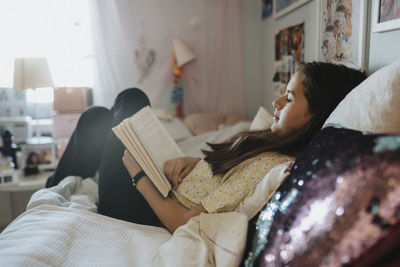 Girl relaxing in bedroom and reading book