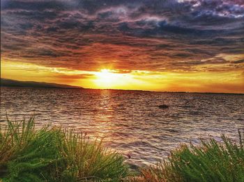 Scenic view of sea against cloudy sky during sunset