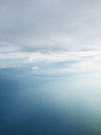 Aerial view of sea against cloudy sky during sunny day