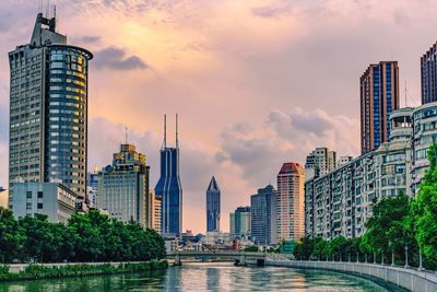 Canal against skyscrapers in city during sunset