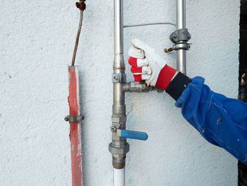 Human hand holding pipe on wall