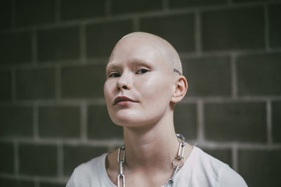 Portrait of bald female activist against wall