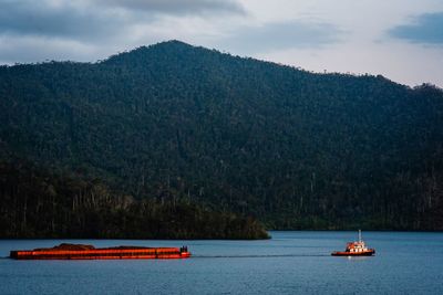 Tugboat carrying barge that contains nickel ore passing a gulf