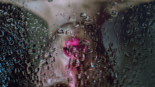 Reflection of man wearing lipstick seen in wet mirror