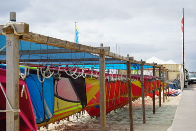 Multi colored flags hanging on wooden post against sky