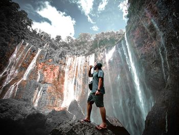 People standing on rock against waterfall