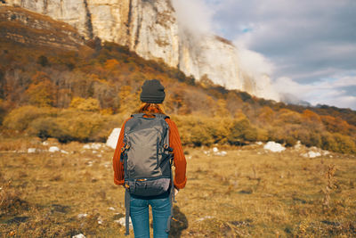 Rear view of man standing on rock against sky